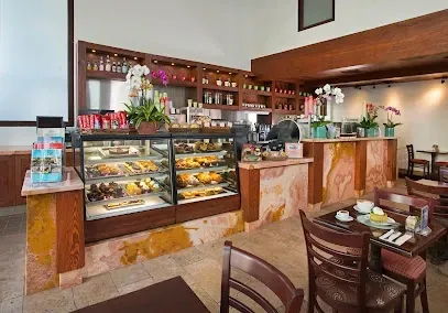 A restaurant with tables and chairs and a display case of food.