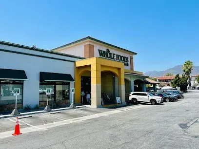 A whole foods store with cars parked in front of it.