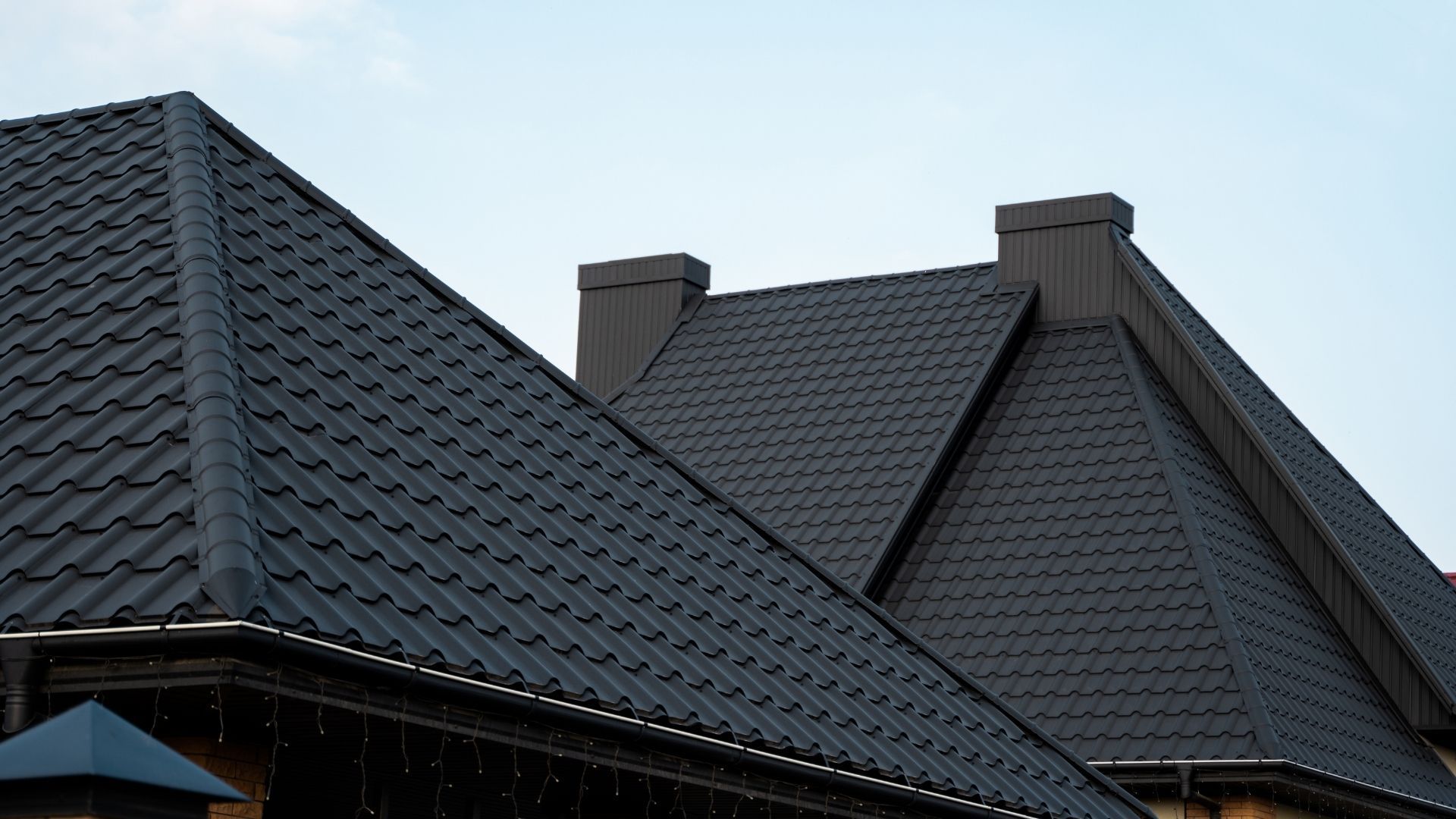 A close up of a house 's roof with a blue sky in the background.