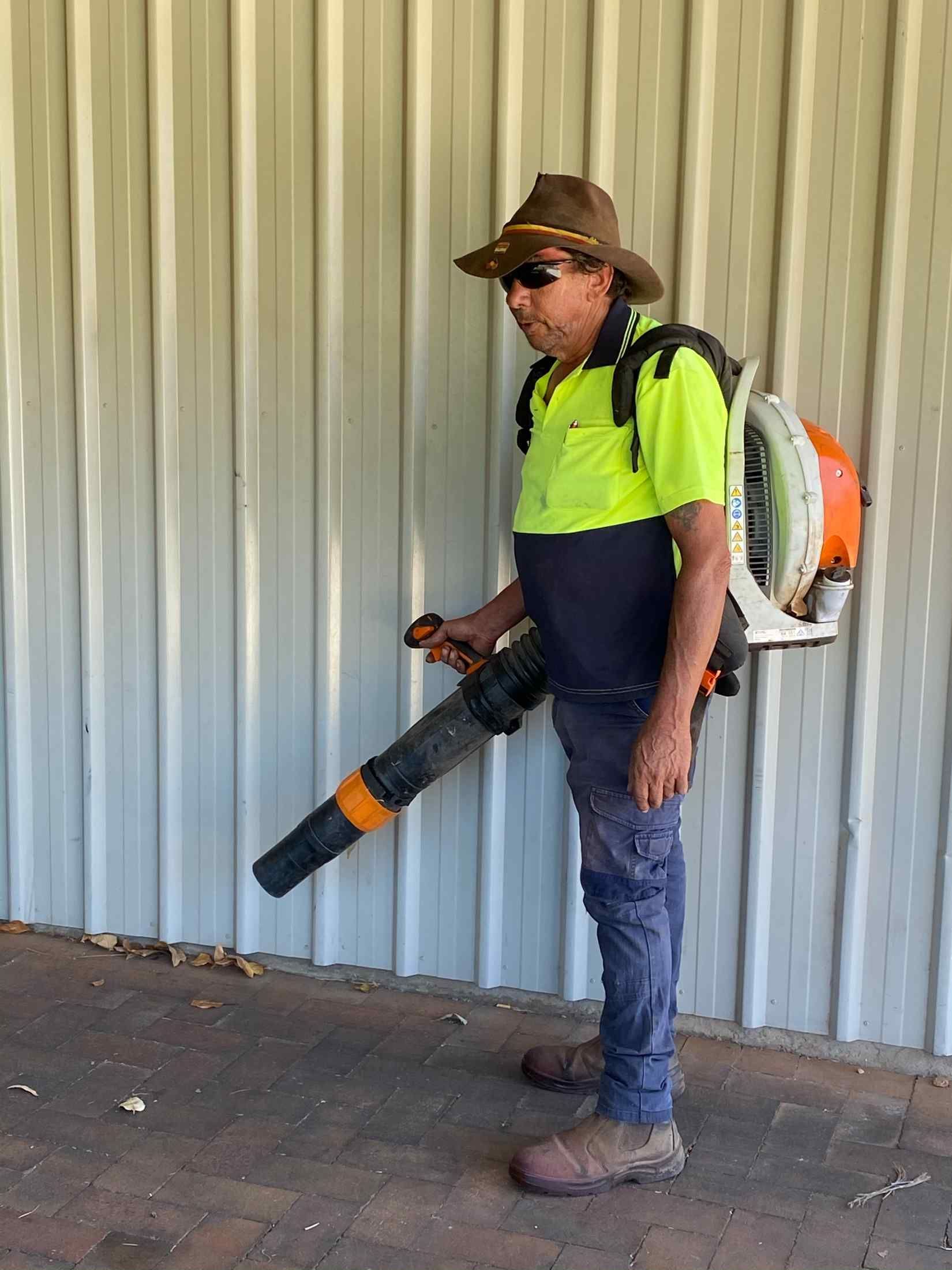 Person Wearing a Hat and Backpack Leaf Blower, Standing Outdoors — Darrell's Mowing Services in Sunset, QLD