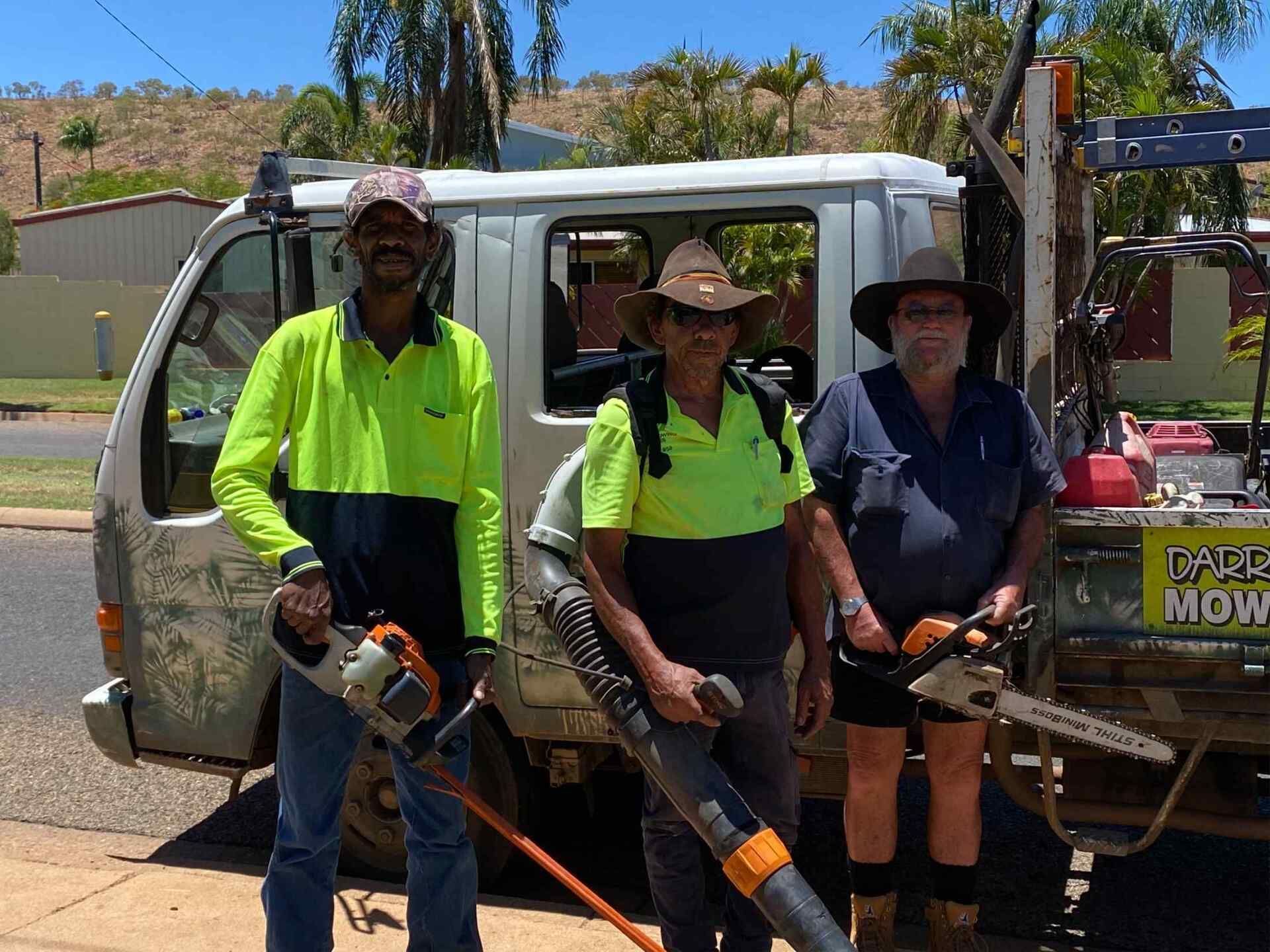 Three People With Yard Tools Stand Near a Work Truck on a Sunny Day — Darrell's Mowing Services in Sunset, QLD