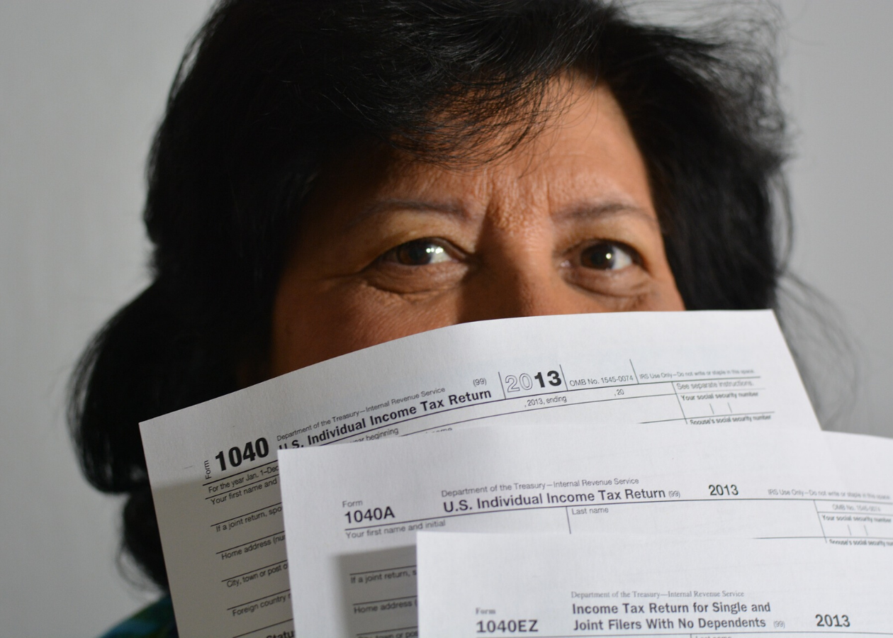 a woman covering her face with a 1040 tax form