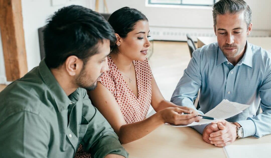a man and a woman are sitting at a table looking at a piece of paper .