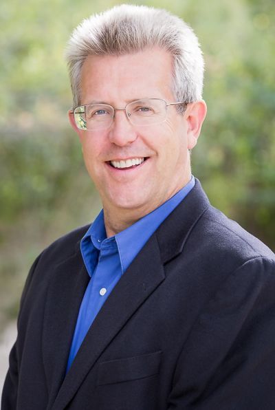 A man in a suit and blue shirt is smiling for the camera.