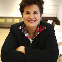 A woman wearing a black jacket and a red and white shirt smiles for the camera