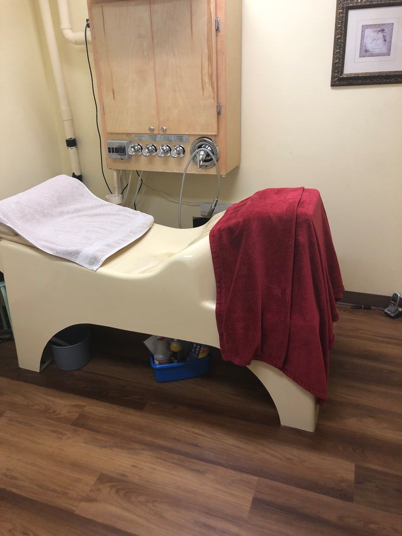 A white bed with a red towel on it in a room.