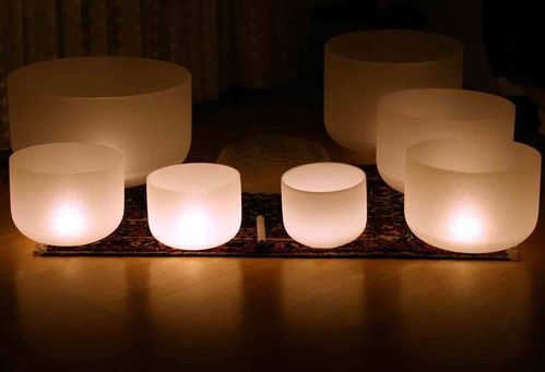 A group of crystal singing bowls are lit up in a dark room.