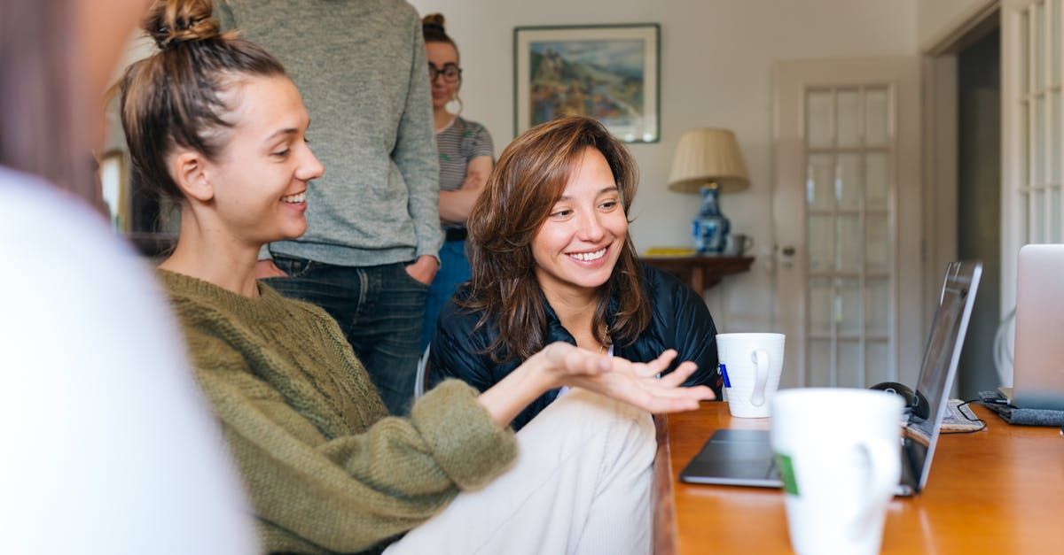 A group of women are sitting at a table talking to each other.