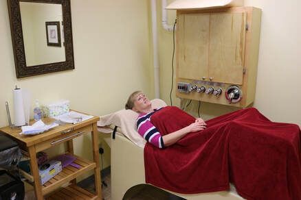 A woman is laying on a bed with a red blanket in a room.