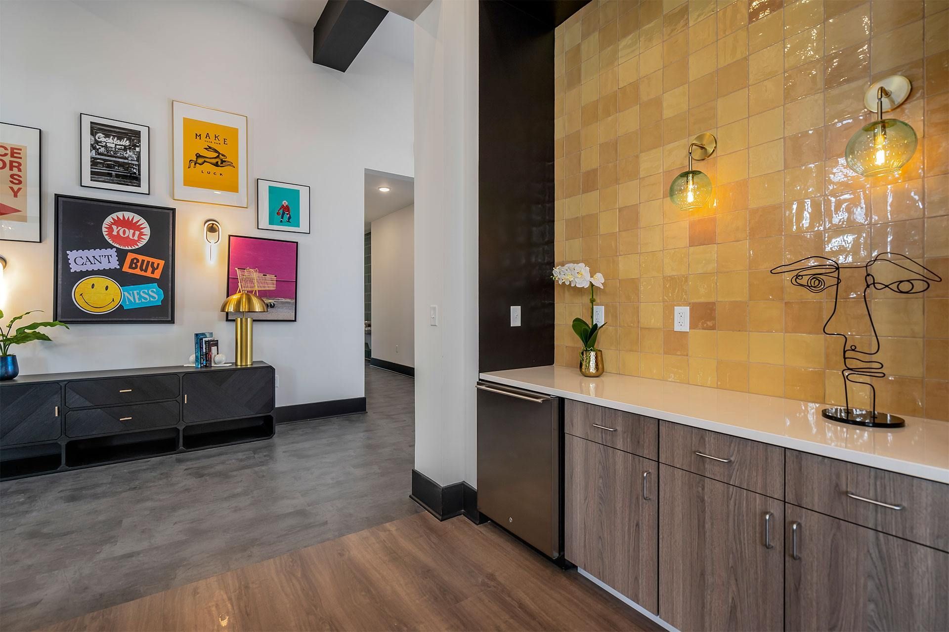 A kitchen with a wooden floor and a wall with a tiled pattern.