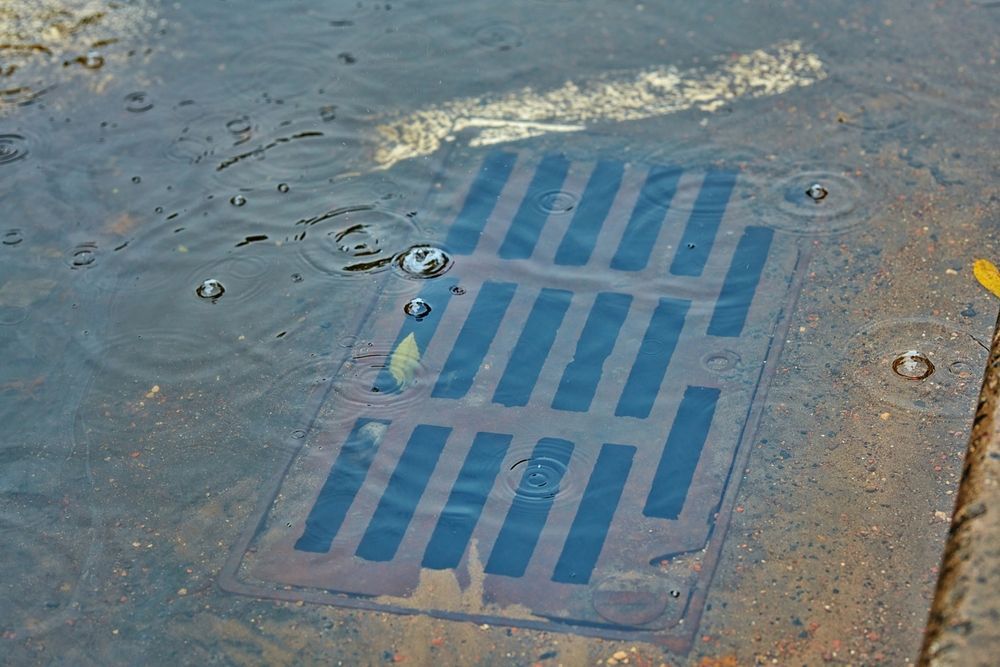 A manhole cover is sitting in the middle of a puddle of water.