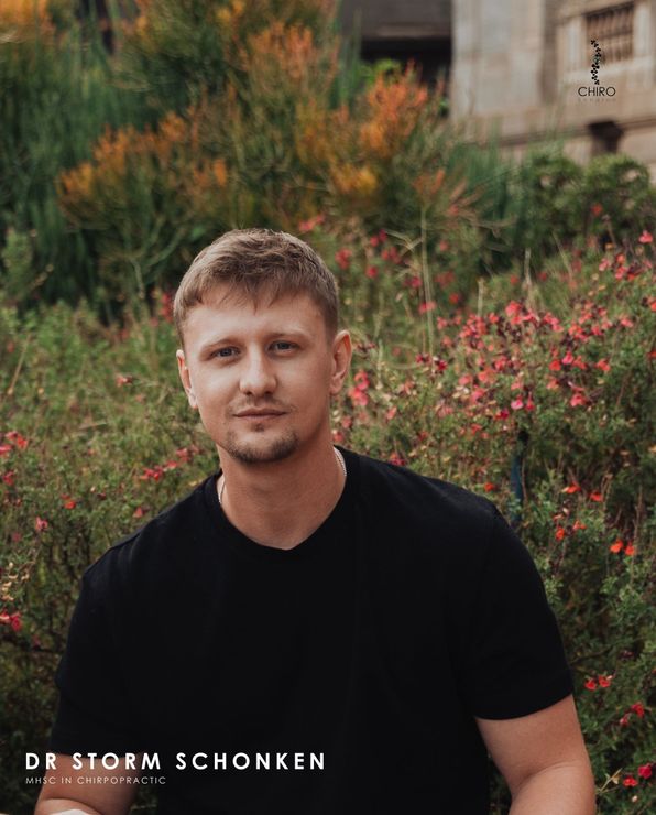 A man in a black shirt is standing in front of a field of flowers.