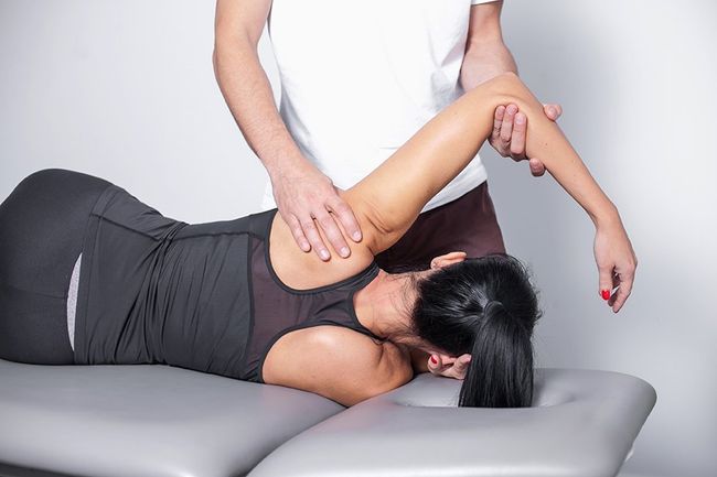 A woman is laying on a table getting a massage from a man.