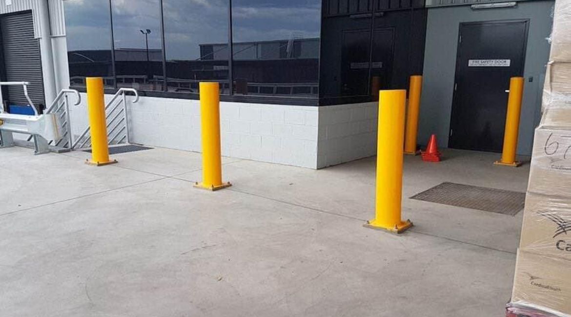 A row of yellow poles are lined up in front of a building.