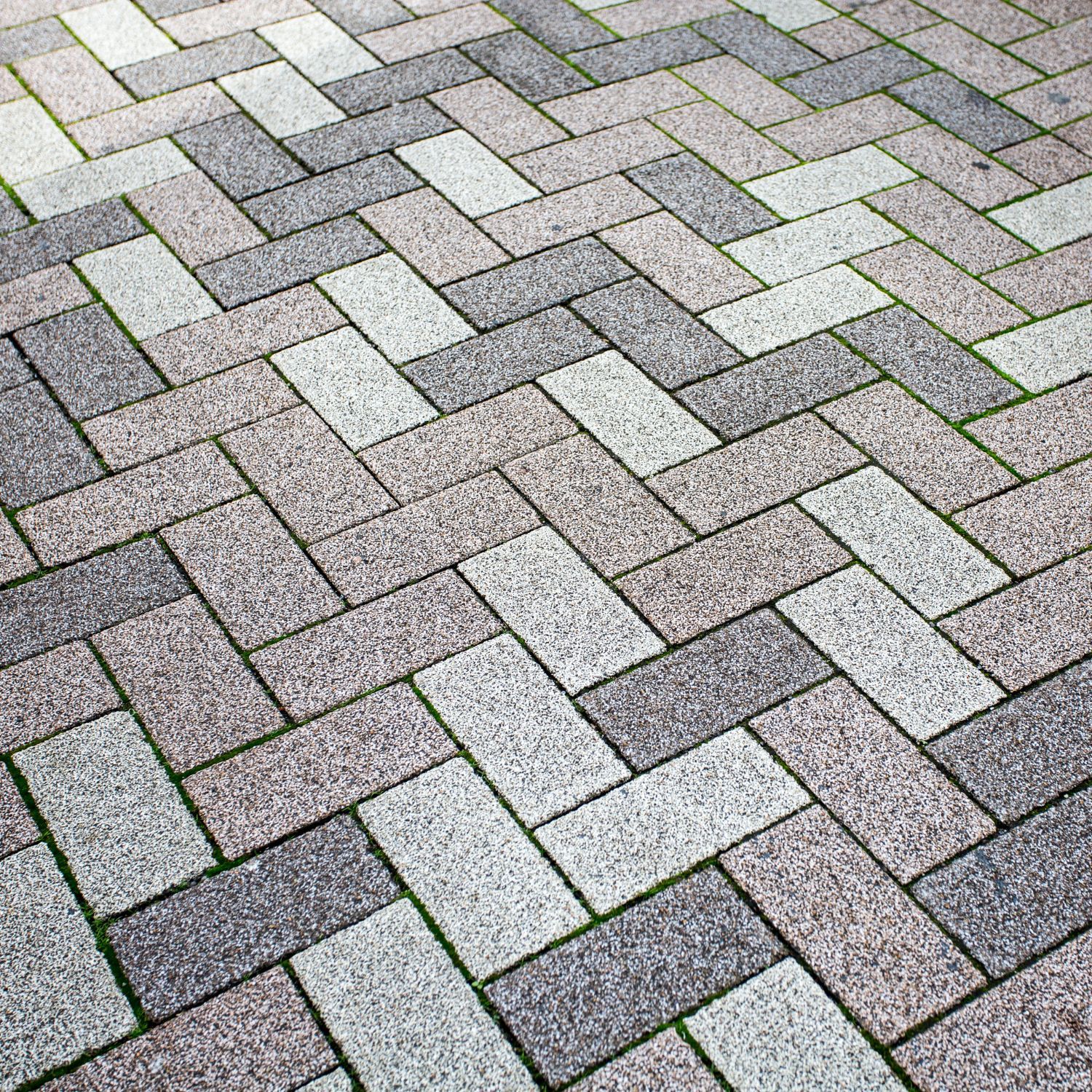 A close up of a brick walkway with a herringbone pattern.