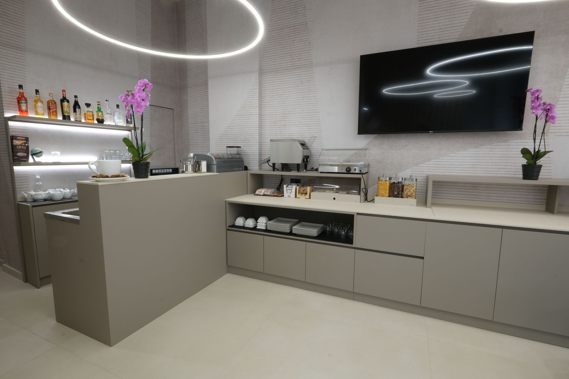 Кухня с барной стойкой и телевизором с плоским экраном на стене.