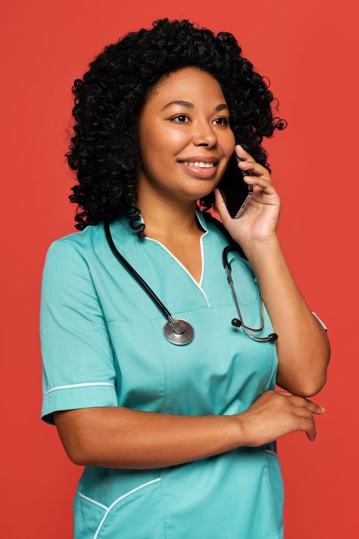 a nurse with a stethoscope around her neck is talking on a cell phone .