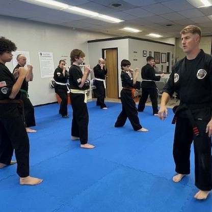 A group of men are practicing karate in a gym.