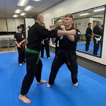 A group of men are practicing karate in a gym.