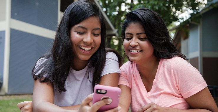 Mother and daughter looking at daughter's phone while smiling