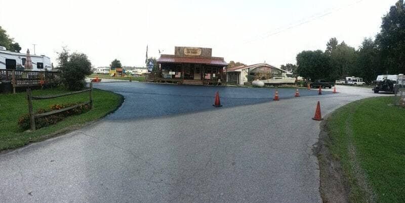 A paved parking lot leads to a rustic, wooden building under a clear sky, marked by several orange traffic cones.