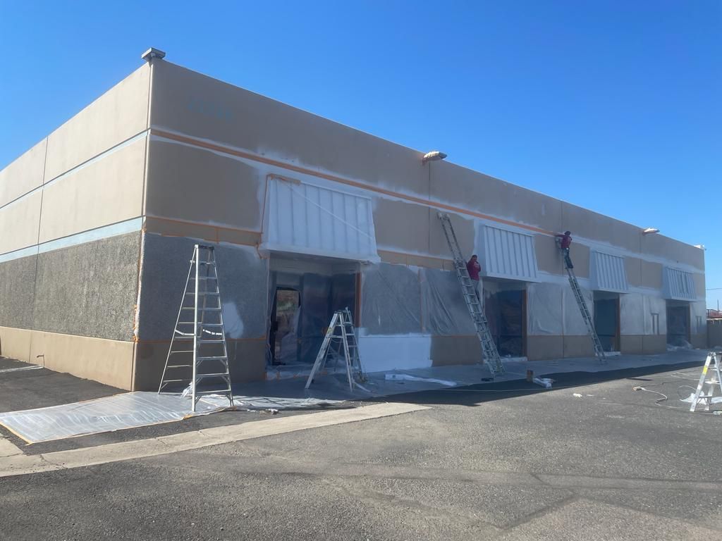 Exterior building being painted. Ladders and scaffolding used for access.