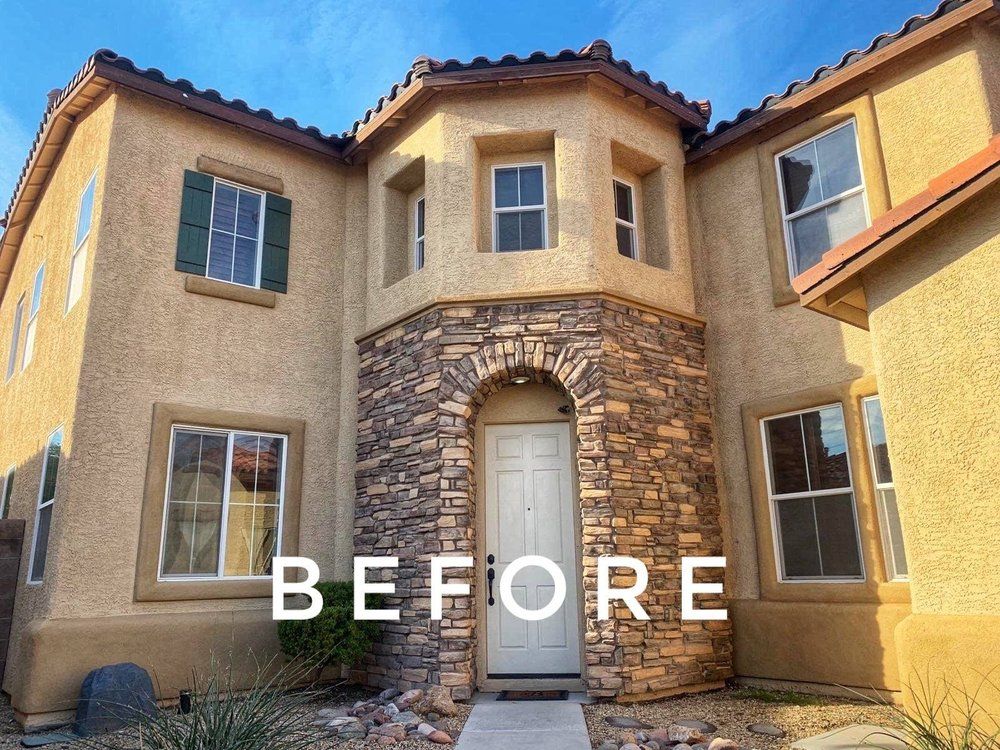 Exterior of a two-story beige house with stone accents, windows, and a white front door. 