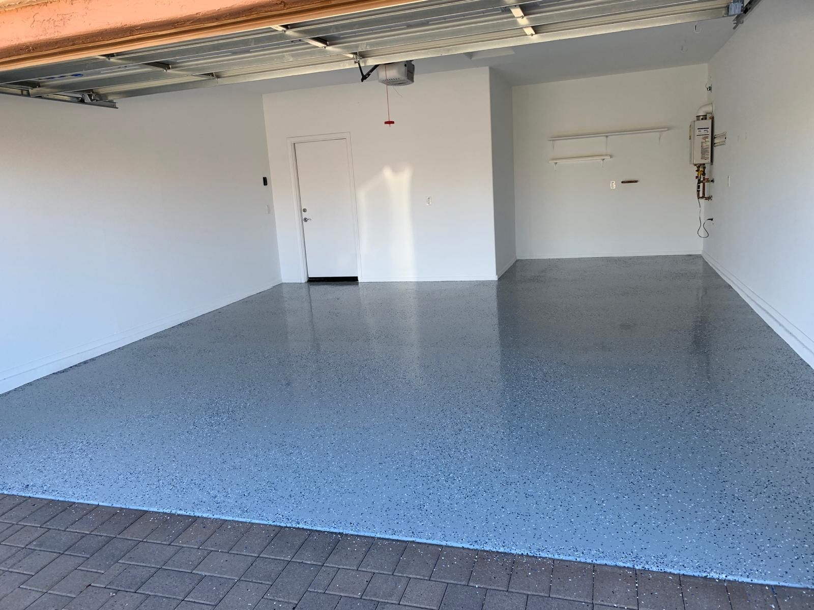 Empty garage with a gray speckled epoxy floor and white walls.