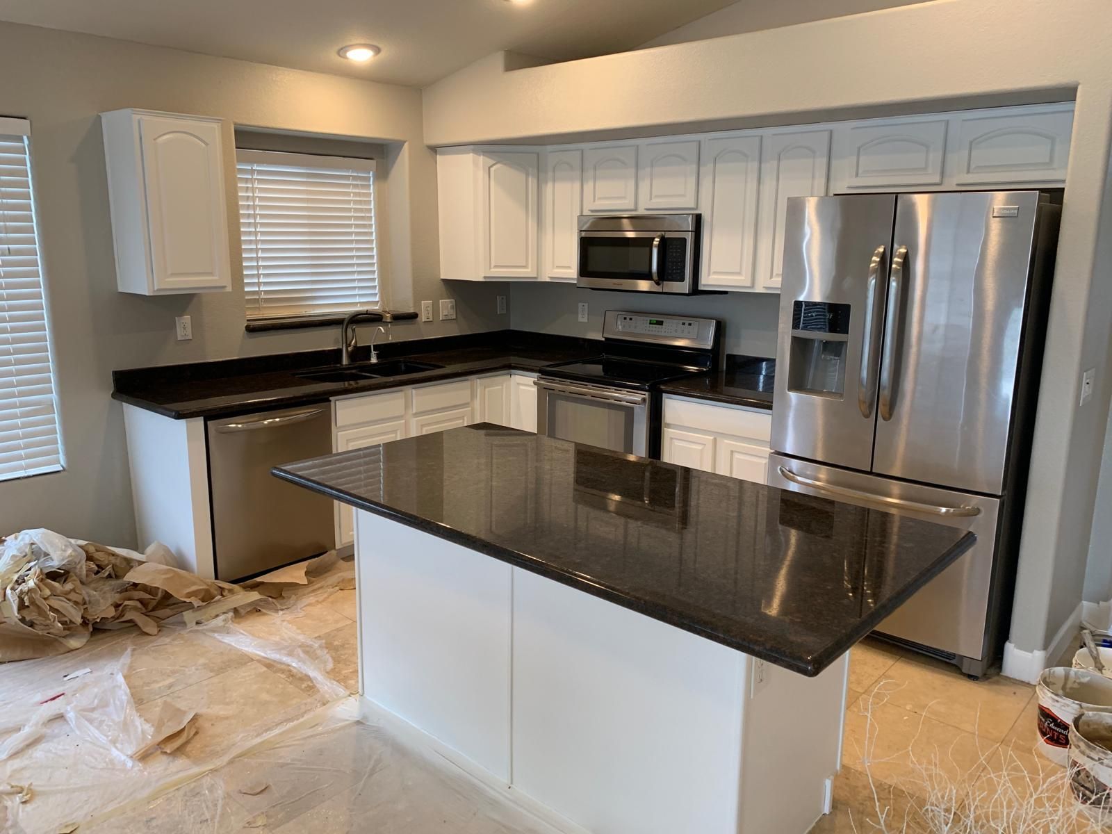 Kitchen with white cabinets, dark countertops, stainless steel appliances, and an island.