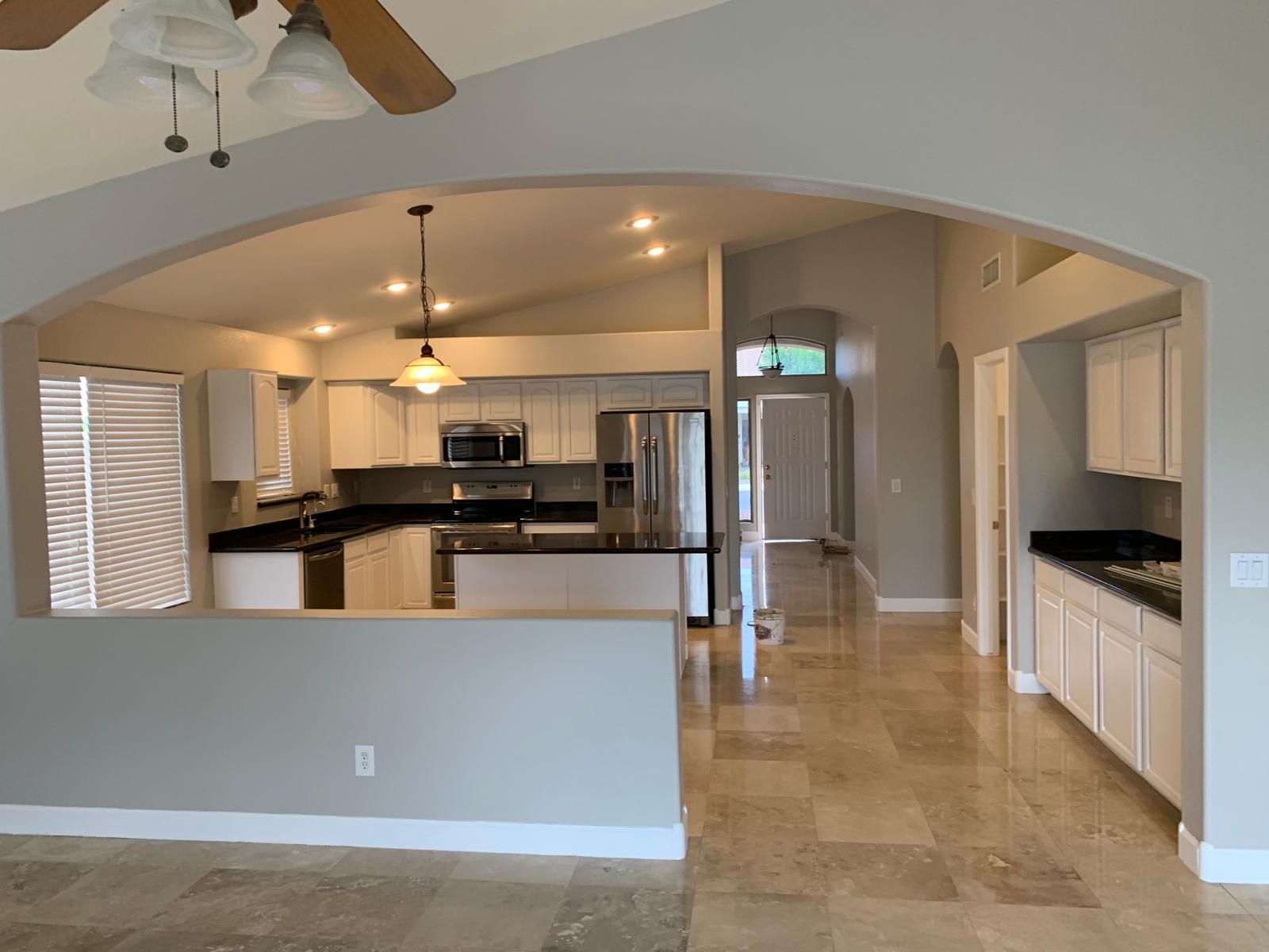 Kitchen with white cabinets, dark countertops, and arched entryway.