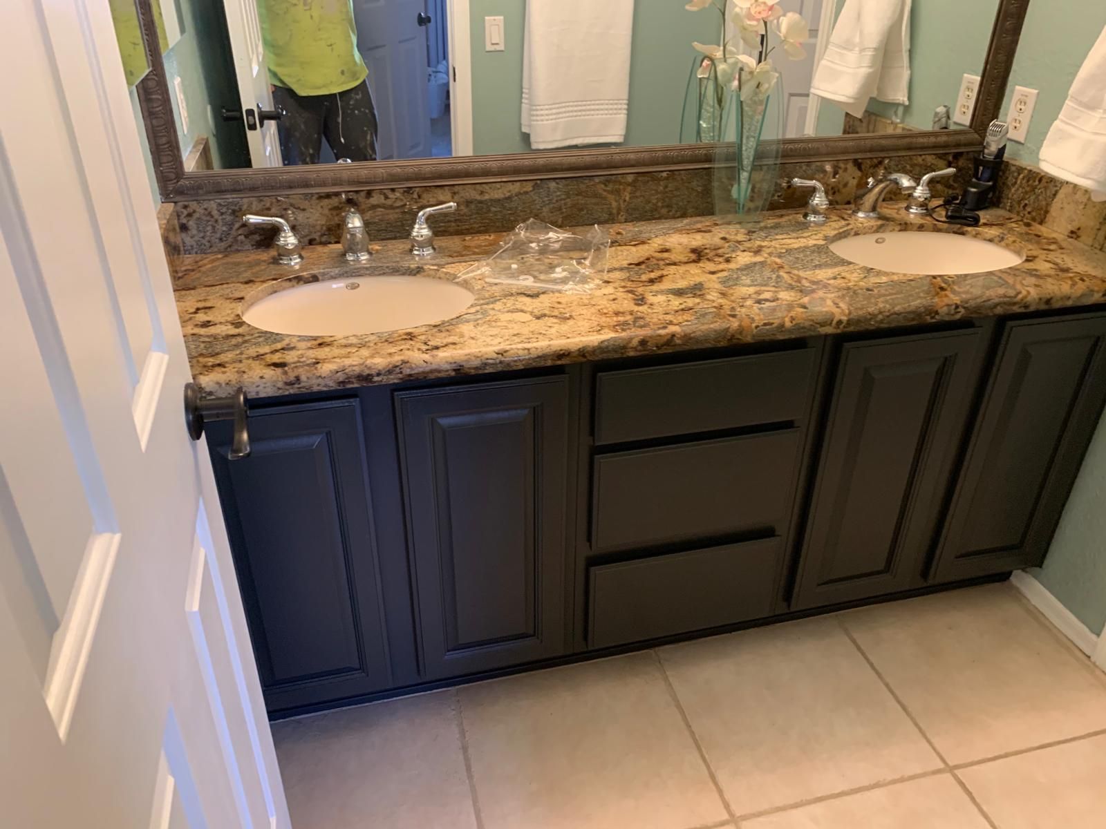 Bathroom vanity with dark cabinets, granite countertop, two sinks, and mirror.