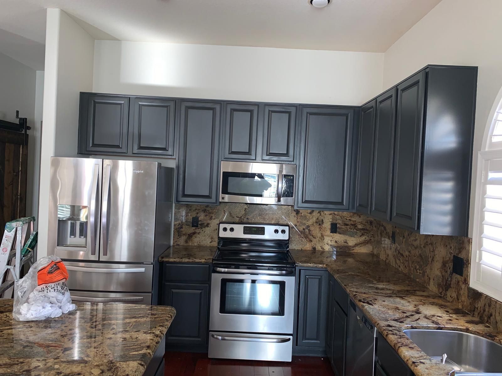 Gray kitchen cabinets with stainless steel appliances and granite countertops.