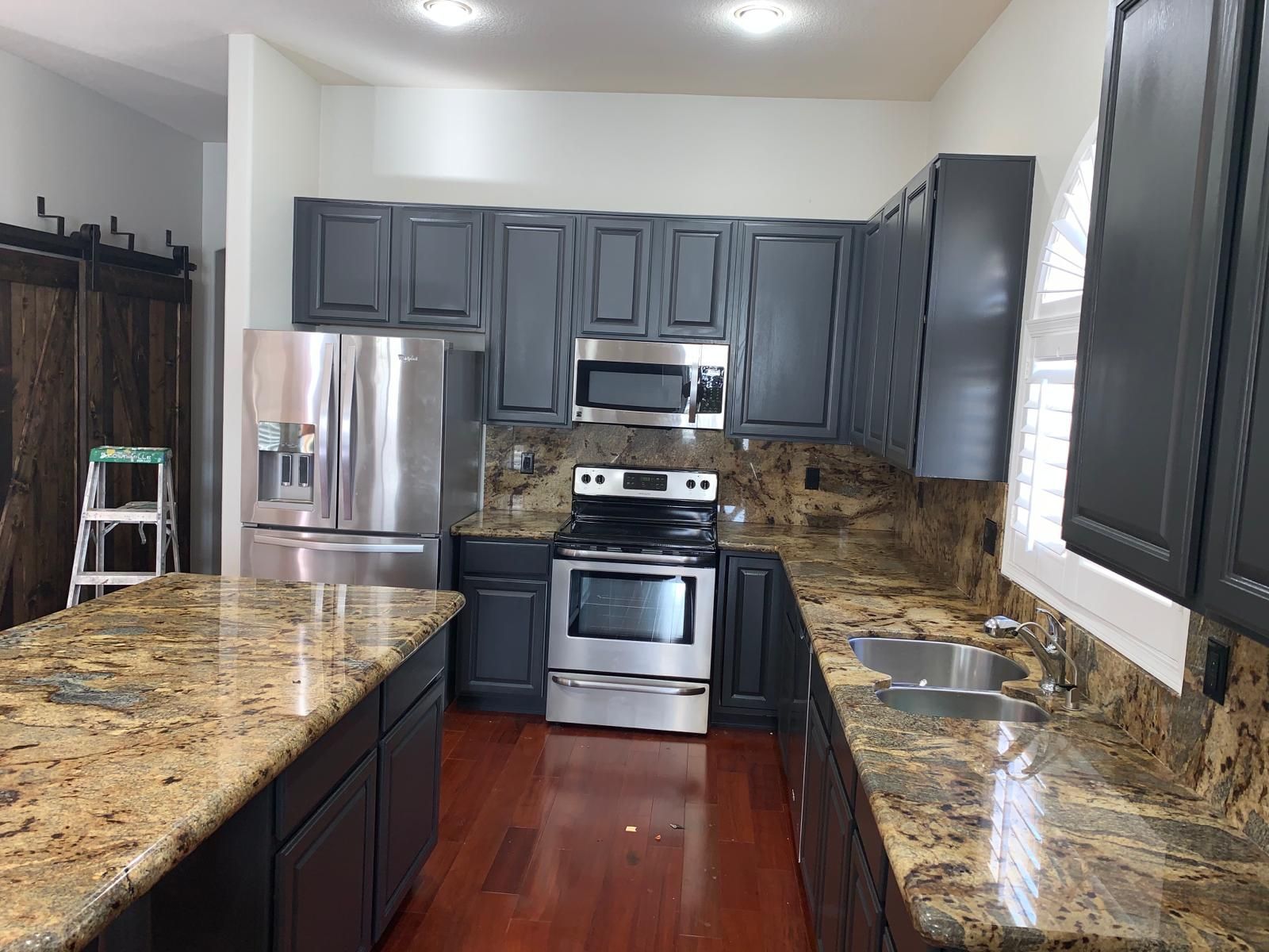 Kitchen with dark gray cabinets, stainless steel appliances, and granite countertops.