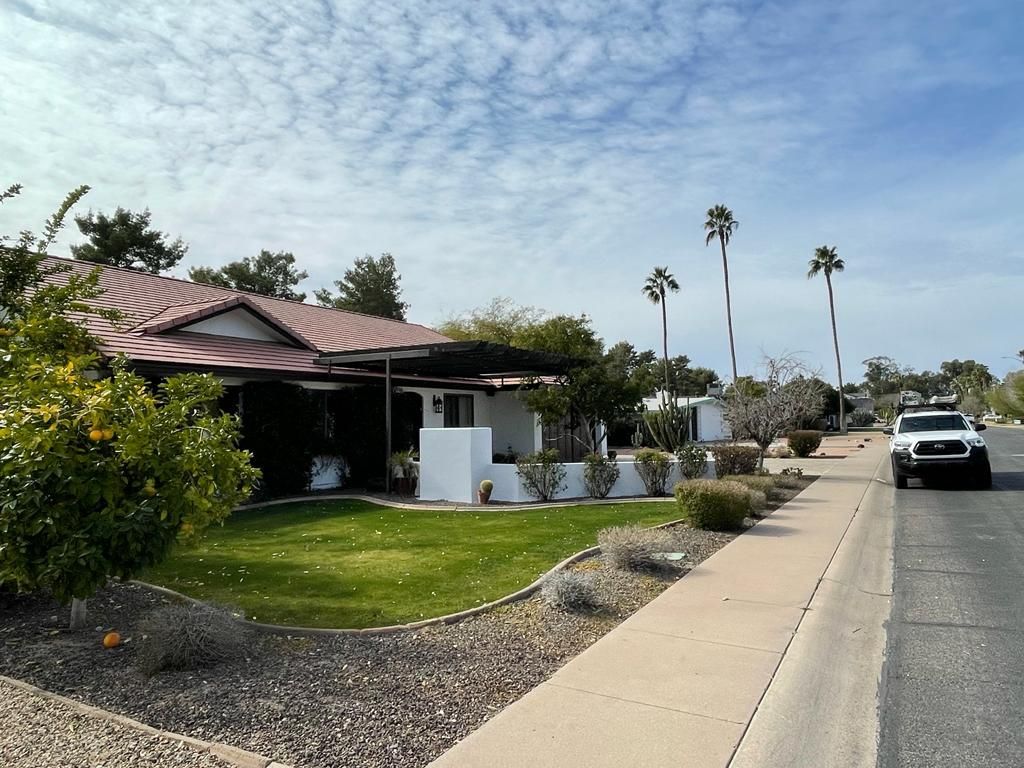 Residential street with houses, green lawn, palm trees, and a white truck.