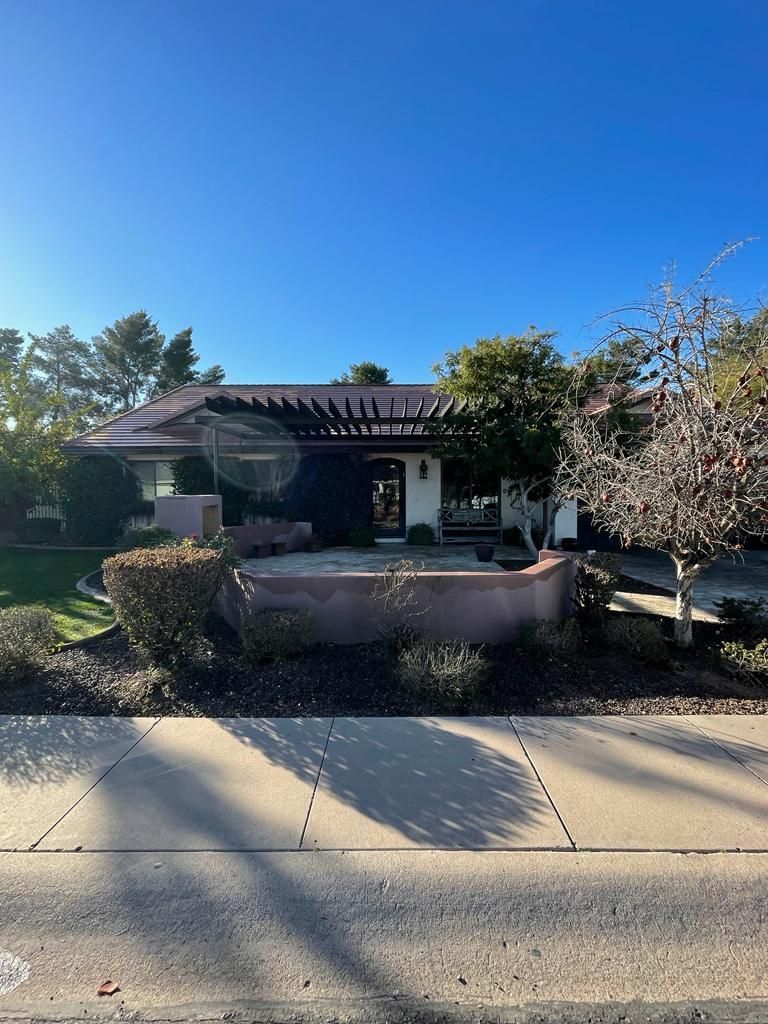 Single-story building with a red tile roof and a dark pergola over the entrance. Sunny day.