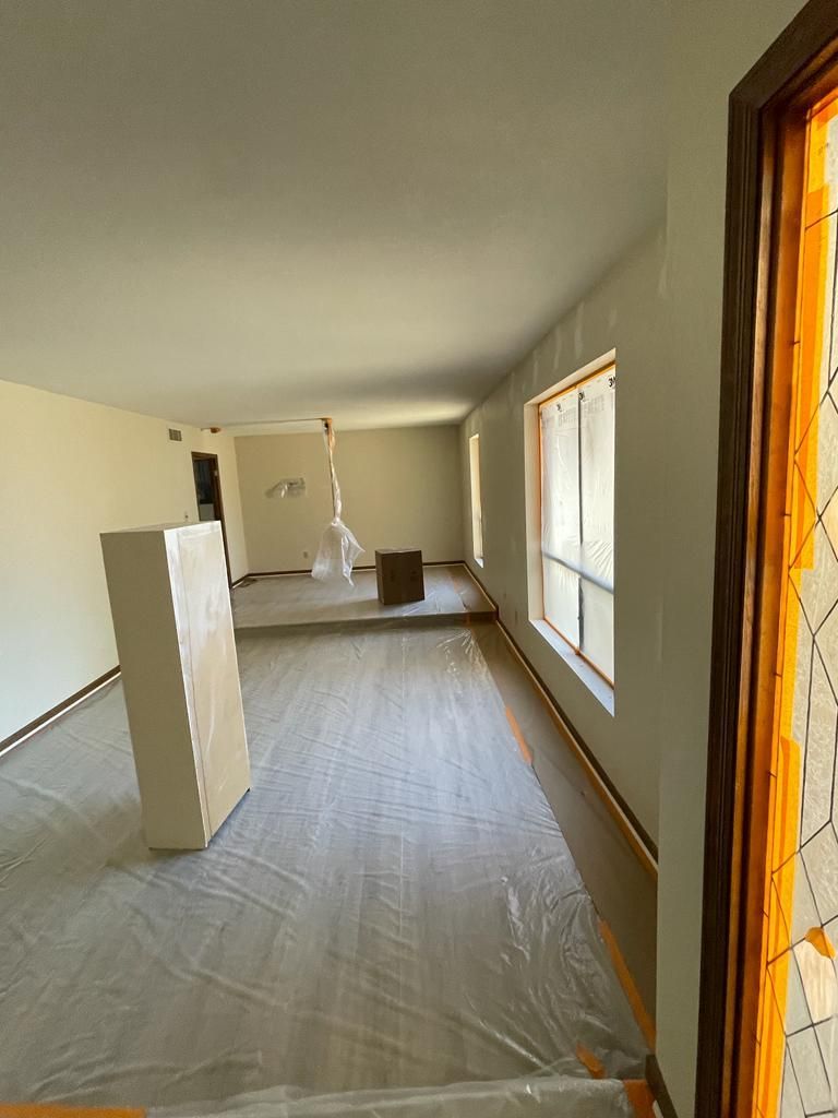 Renovated room: plastic floor covering, two windows with light shining through, and a stained glass door frame.