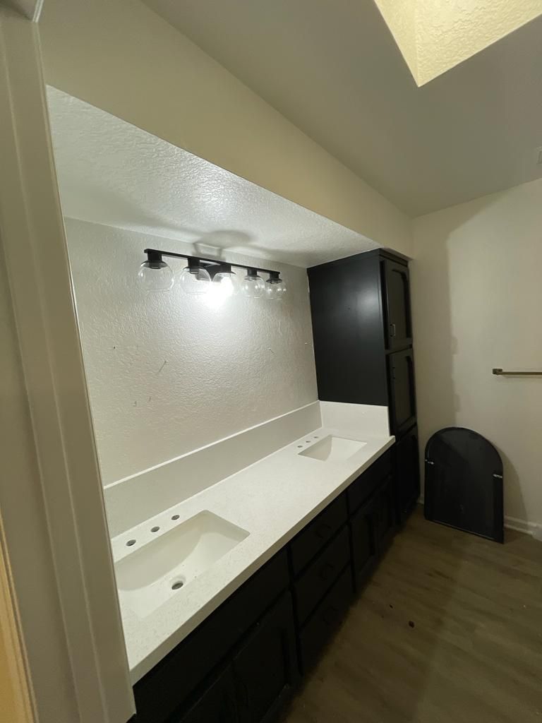 Bathroom with black vanity, white countertop, and wall-mounted light fixture.