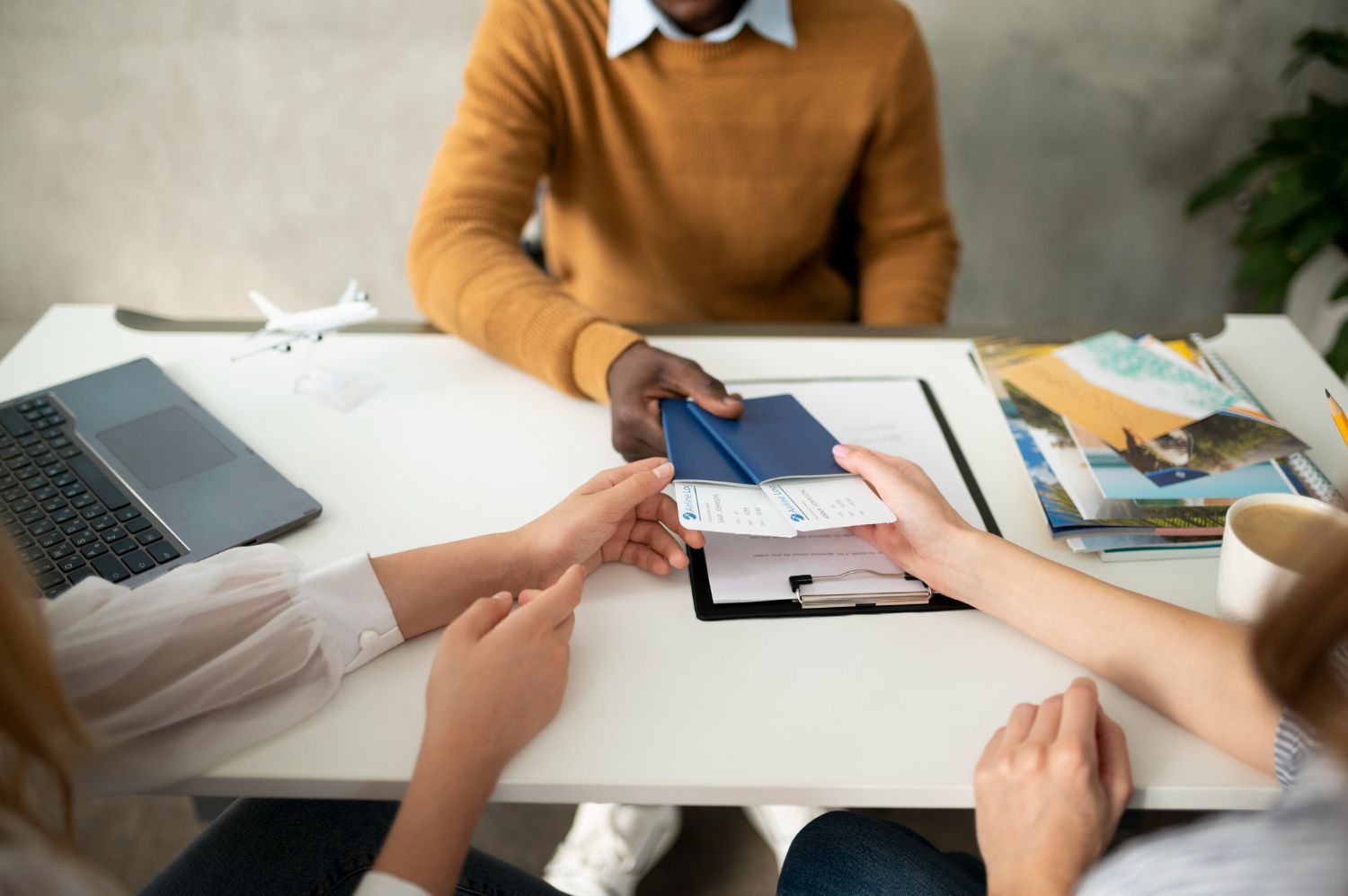 A group of people are sitting around a table holding passports.