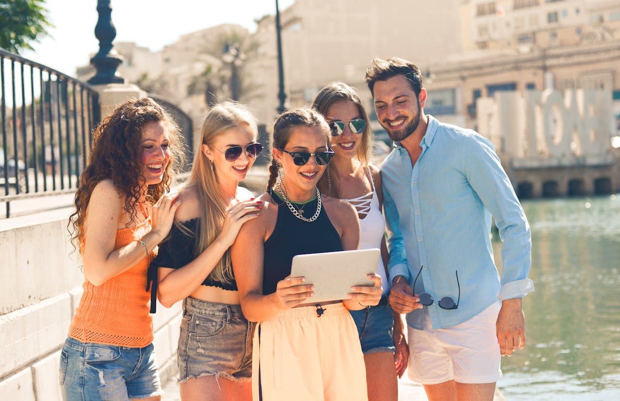 A group of young people are standing next to each other looking at a tablet.