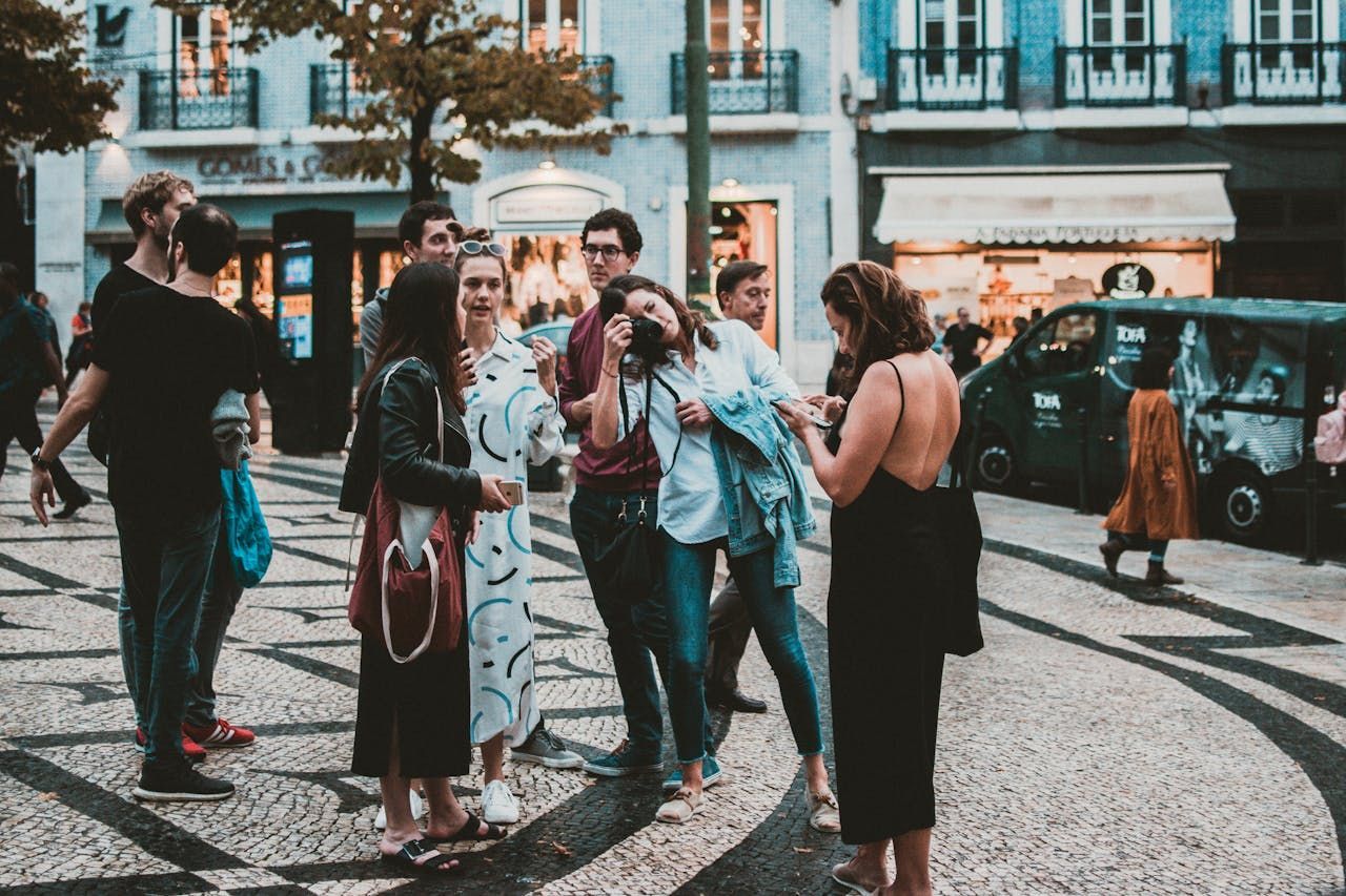 A woman is taking a picture of a group of people standing on a sidewalk.