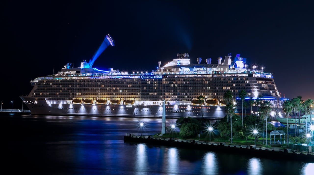 A large cruise ship is docked in a harbor at night.