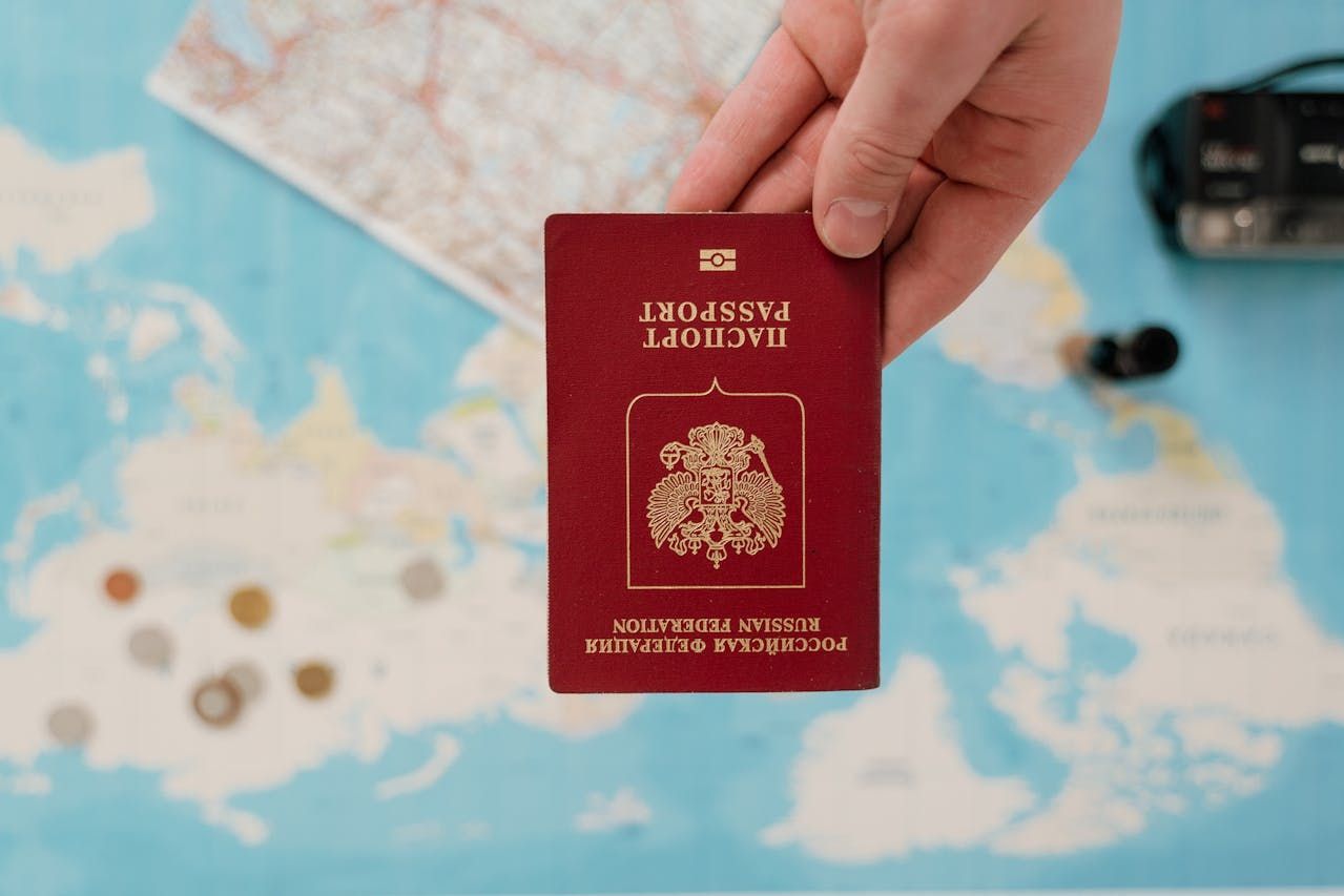 A person is holding a passport in front of a map.