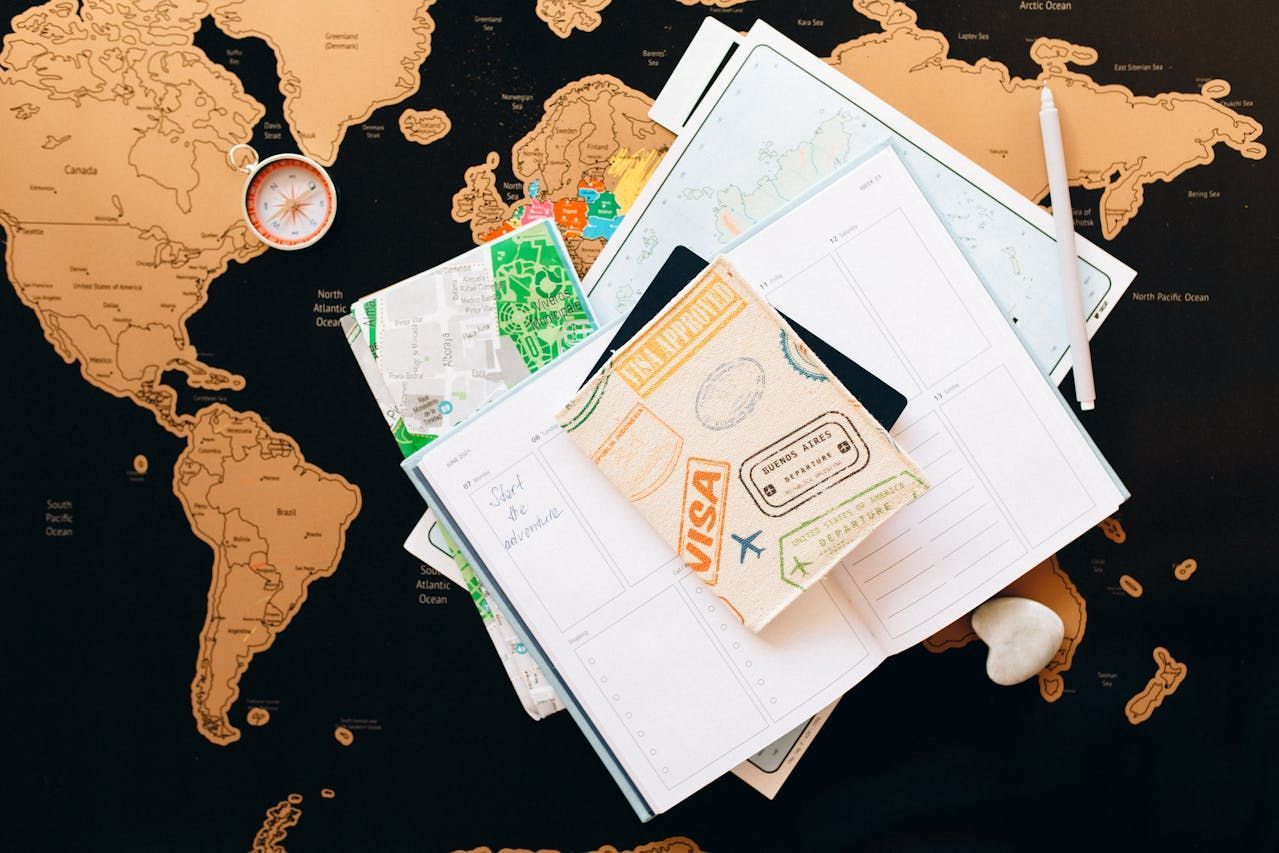 A stack of passports , visas , and maps on a map of the world.