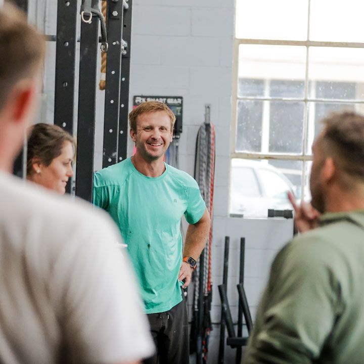 A group of people are standing in a gym talking to each other.