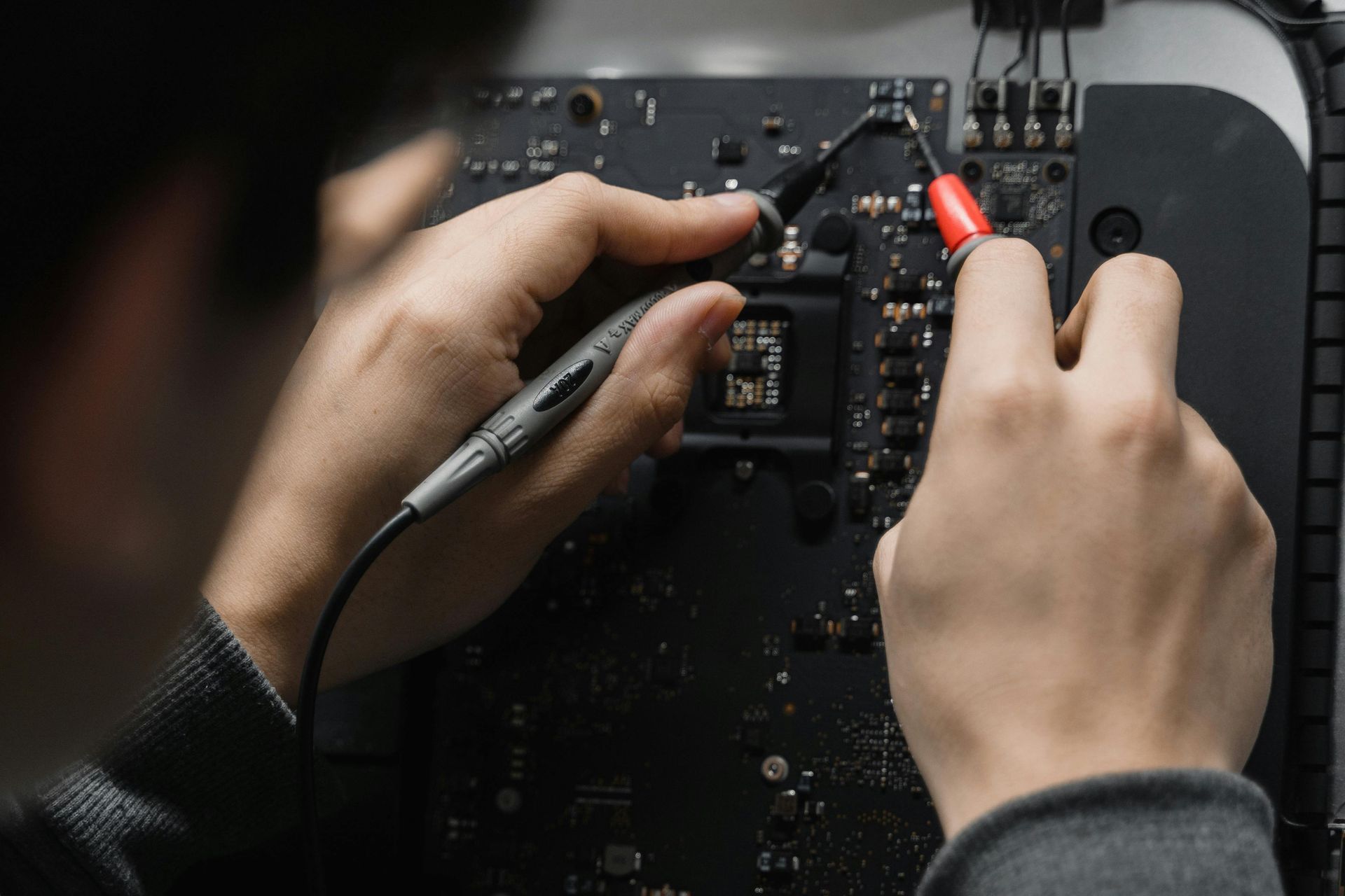 A person is working on a computer with a multimeter.