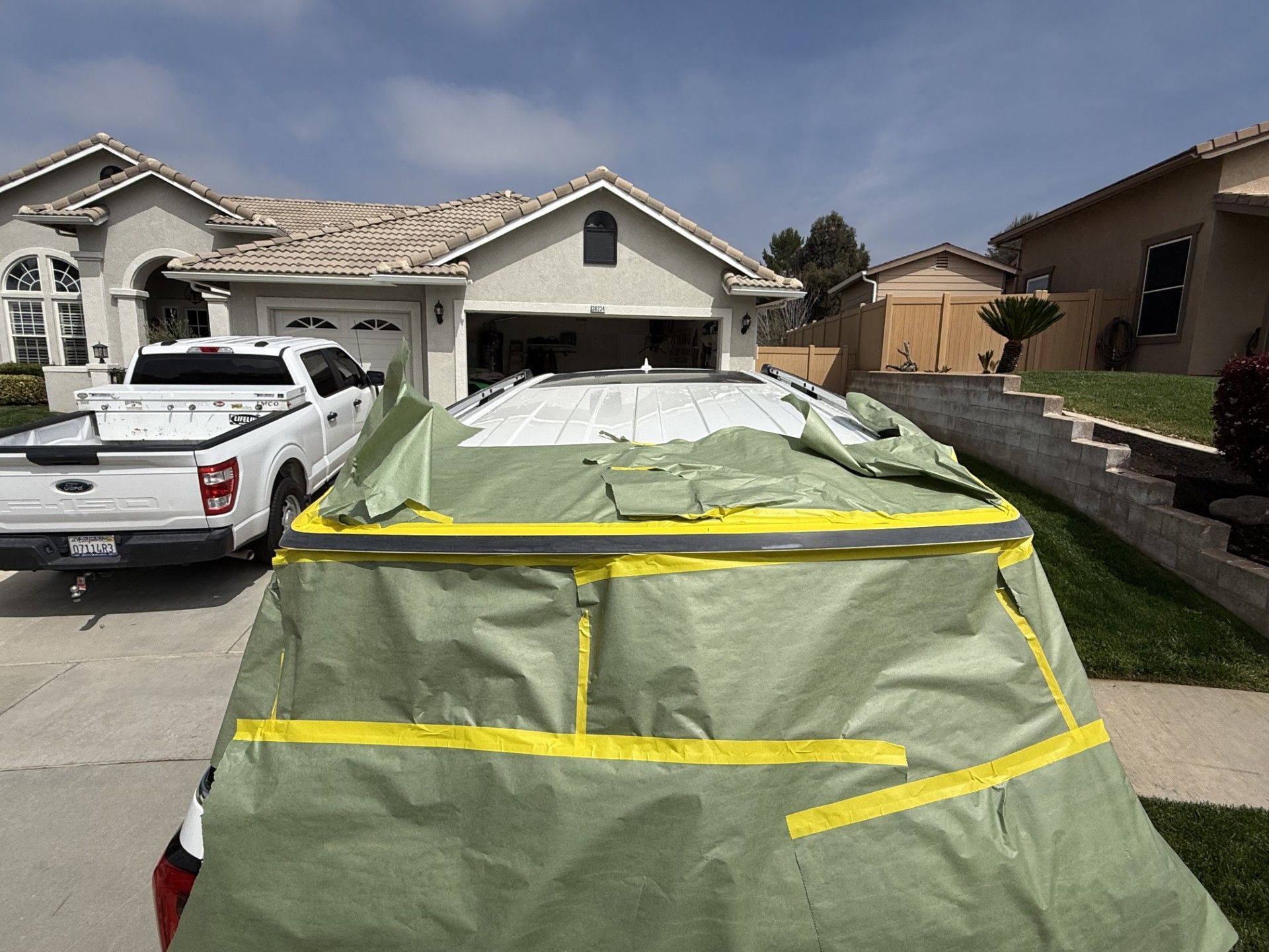 A white truck is parked in front of a house covered in tape.