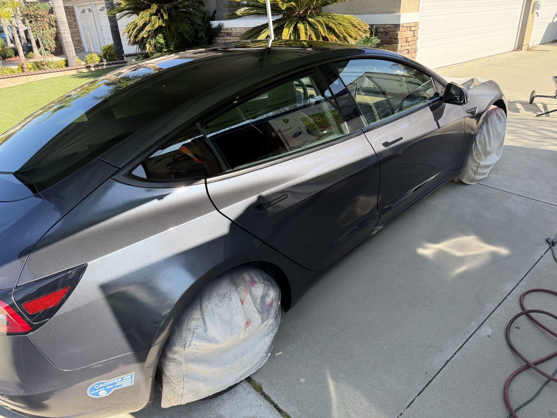 A blue car is sitting on a block with the trunk open
