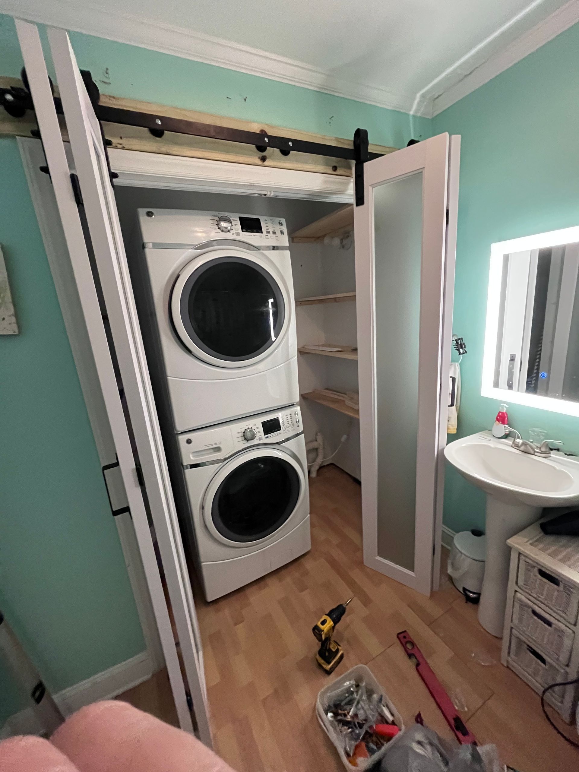 A person in a blue apron and pink gloves uses a vacuum cleaner to deep clean a tufted light-colored sofa.