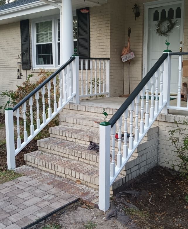 Front porch with brick steps, white railings with dark caps, and a paved walkway leading to the entrance.