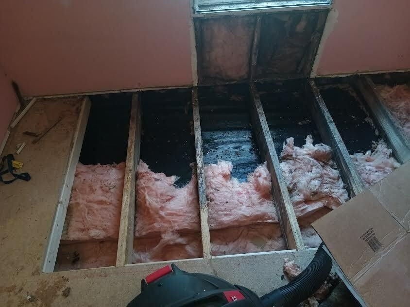 An exposed floor section reveals joists and pink fiberglass insulation, with a dark subfloor beneath.